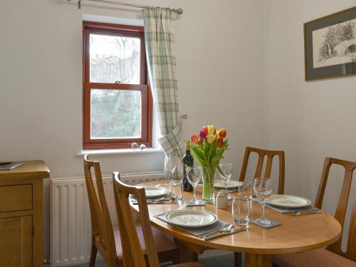 a dining room table with glasses and flowers on it at The Ginnel Mews in Skipton