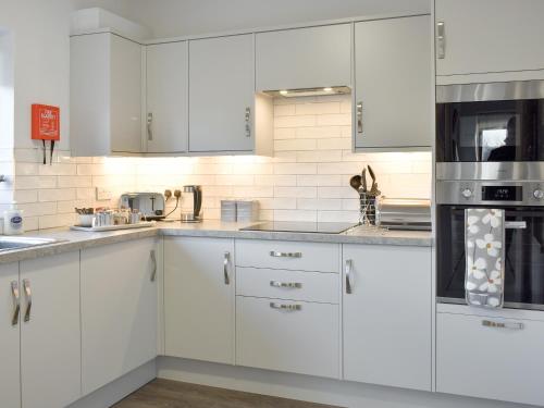 a white kitchen with white cabinets and appliances at The Ginnel Mews in Skipton