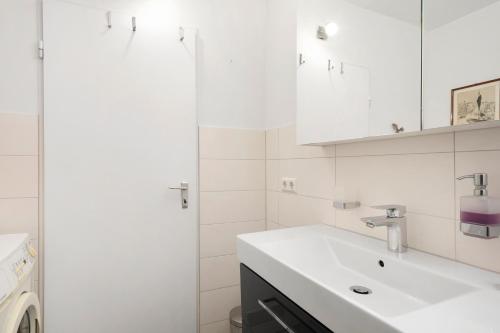 a white bathroom with a sink and a washing machine at Bodenseewohnung Bär in Immenstaad am Bodensee