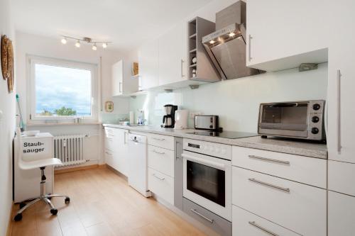 a kitchen with white cabinets and a stove top oven at Bodenseewohnung Bär in Immenstaad am Bodensee