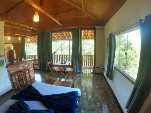a bedroom with a bed and a balcony with a table at Chalé Biribó in Conceição do Mato Dentro