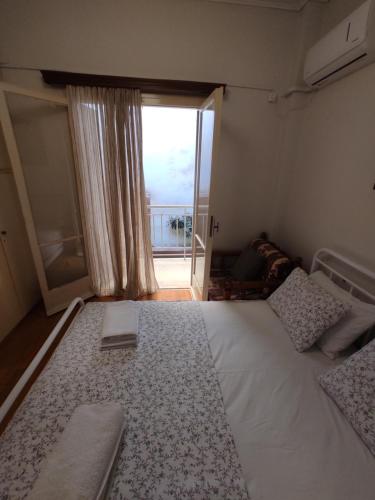 a bedroom with a large bed with a large window at Hellen Guest House in Mesochórion