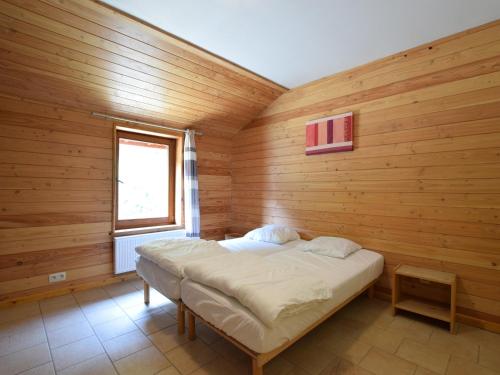 a bed in a wooden room with a window at Rendeux Retreat with Sauna in La Roche-en-Ardenne