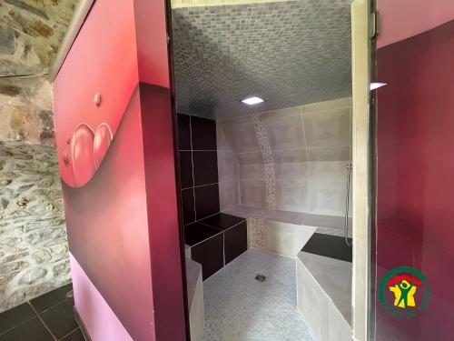 a bathroom with a shower with a pink door at Gite Sublime Spa, Piscine Indoor in Mostuéjouls