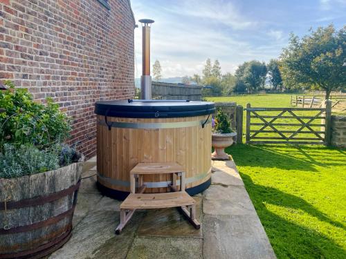 a wooden hot tub with a stool next to a brick building at Mullins Cottage in Gristhorpe