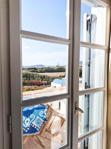 a window with a chair looking out at the beach at My Plaka Beach Vacation Home in Plaka
