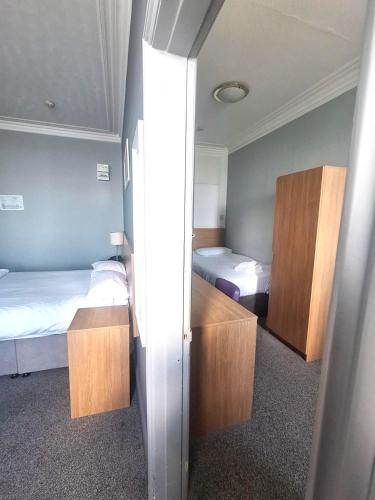 a small bedroom with two beds and a closet at The Burlington Hotel in Eastbourne