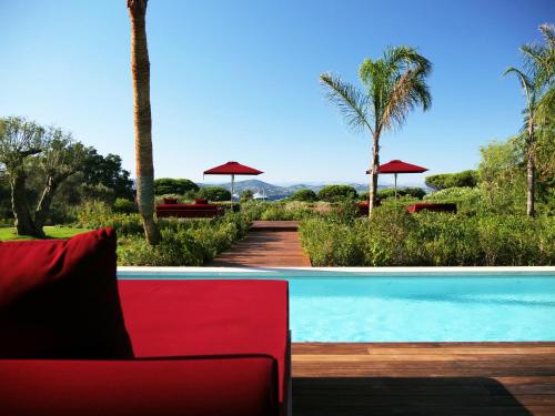 a red couch sitting next to a swimming pool at Vyylla Private Resort in Saint-Tropez