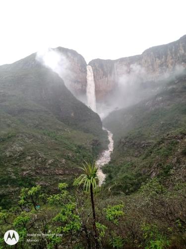 a waterfall in the mountains with a palm tree at Chalé Biribó in Conceição do Mato Dentro