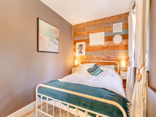 a bedroom with a bed with a wooden wall at Bwythyn Cudd in Manortown