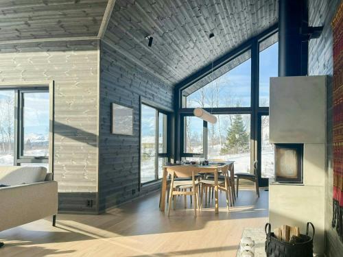 ein Esszimmer mit einem Tisch und einigen Fenstern in der Unterkunft Mountain Cabin With Beautiful Lake View in Markegardlian