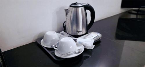 a tea kettle and saucers on a table at Lake View Resort by TropiCube in Pamunugama