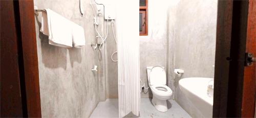 a white bathroom with a toilet and a sink at Lake View Resort by TropiCube in Pamunugama