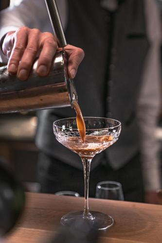 a man pouring a cocktail into a martini glass at Verwöhnhotel Wildspitze in Sankt Leonhard im Pitztal