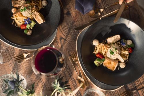 two plates of food and a glass of wine on a table at Verwöhnhotel Wildspitze in Sankt Leonhard im Pitztal