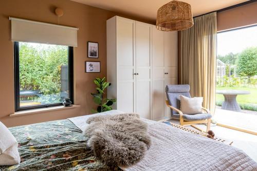 a bedroom with a bed and a chair and a window at Designer Cabin With Guest House At Lake Mullsjö in Skogslund