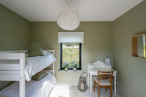 a bedroom with two bunk beds and a table and a chandelier at Designer Cabin With Guest House At Lake Mullsjö in Skogslund