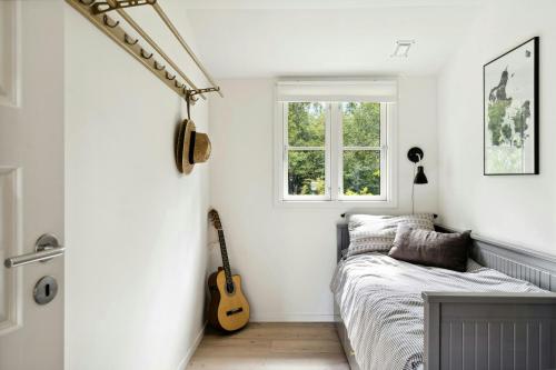 MunkerupにあるThe Small Oasis With Beach Vibes In Dronningmølleのベッドルーム(ベッド1台、ギター付)
