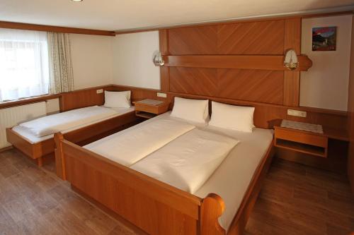 two beds in a small room with wood paneling at Haus Helga in Kappl