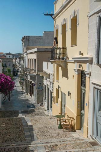 a woman standing on a balcony of a building at Domino Syros by SV in Ermoupoli