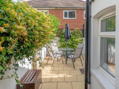 a patio with a table and chairs and an umbrella at Mcenroe Cottage in Broadstairs