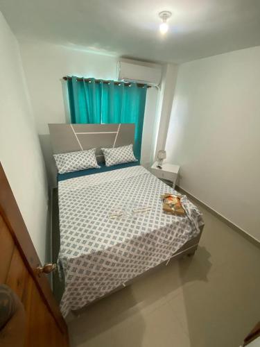 a small bedroom with a bed with a blue curtain at Beautiful apartment near STGO airport in Santiago de los Caballeros