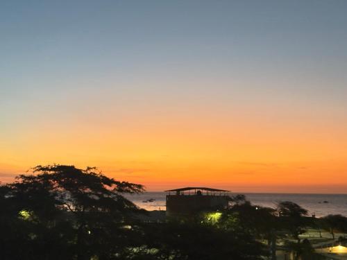 a sunset over the ocean with trees in the foreground at Hospedaje Casa Aluha in Los Órganos