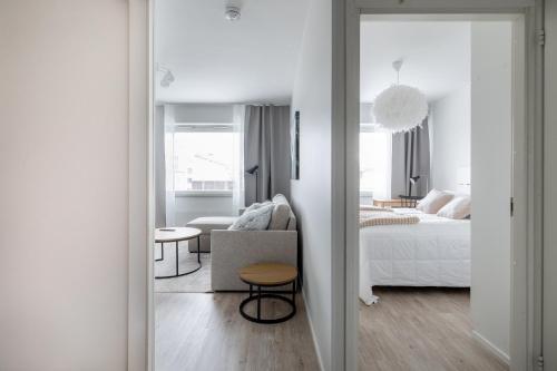 a white bedroom with a bed and a chair and a table at Santas Arctic Aurora in Rovaniemi