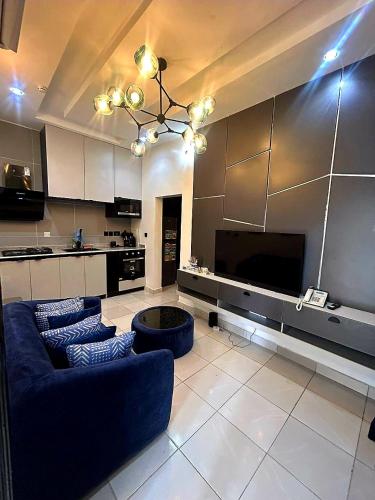 a large living room with a blue couch and a tv at Cute One bedroom with swimming pool Victoria Island in Lagos