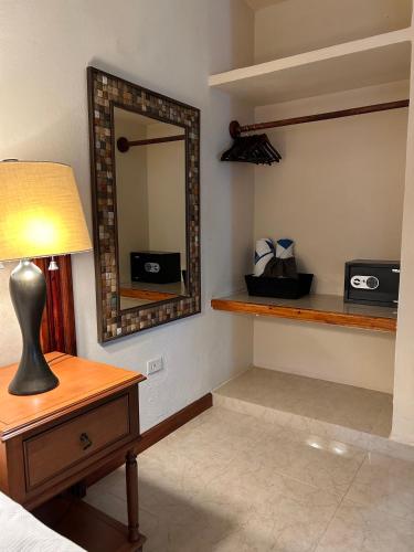 a bedroom with a mirror and a table with a lamp at The Diving Lodge Downtown in Puerto Morelos