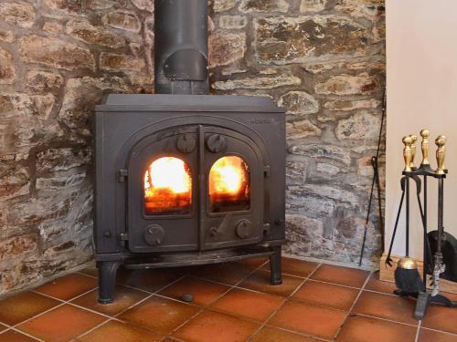 a wood stove in a room with a stone wall at Arkland Mill in Corsock