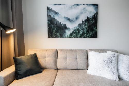 a couch in a living room with a picture of a forest at Santas Arctic Aurora in Rovaniemi