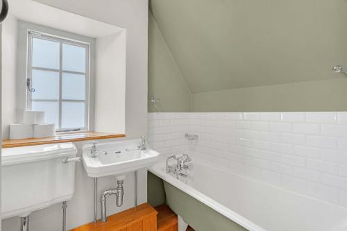 a white bathroom with a sink and a bath tub at Church Cottage in Burford