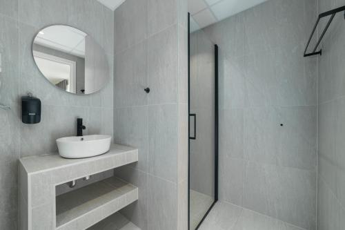 a bathroom with a sink and a mirror and a shower at MAYA Apartments - Trondheimsveien 84-86 in Oslo