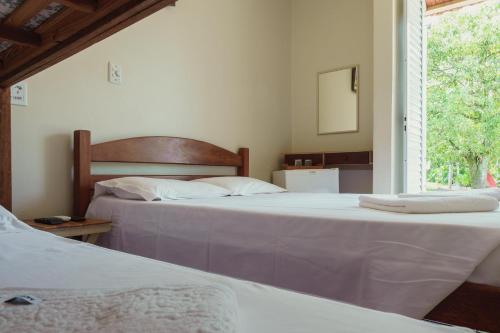 two beds in a bedroom with a window at Hotel Alto da Boa Vista in Analândia