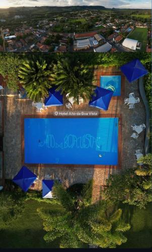 an overhead view of a swimming pool with blue umbrellas at Hotel Alto da Boa Vista in Analândia