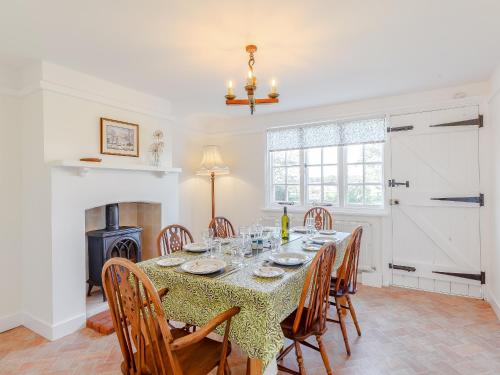 a dining room with a table with chairs and a fireplace at Mark Farmhouse in Bradwell on Sea