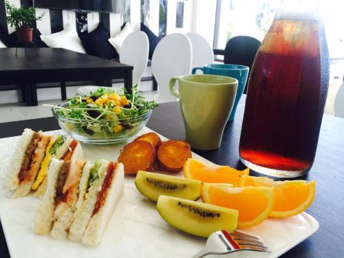 ein Teller mit Sandwiches und Obst und ein Getränk auf dem Tisch in der Unterkunft Stick-On B&B in Shunan