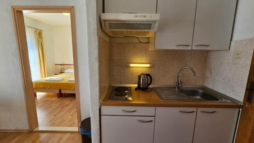 a small kitchen with a sink and a bed at Apartmani Igrane 3 in Igrane