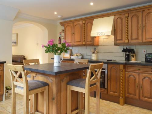 a kitchen with wooden cabinets and a table with chairs at Victoria House - Uk13380 in Llanstephan