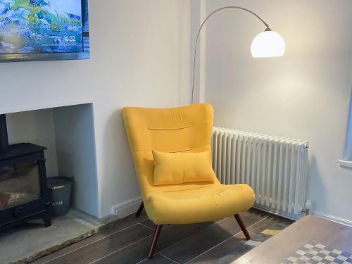 a yellow chair sitting in a living room next to a fireplace at The White Cottage in Gargrave