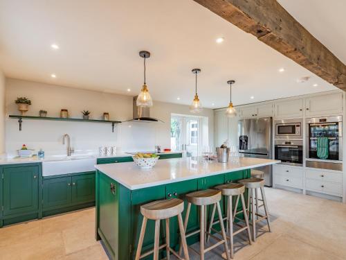 a kitchen with green cabinets and a large island with bar stools at Buryemwick in Timble