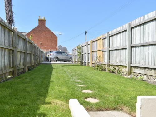 a fence with grass and stones in a yard at Newstead Cottage in Weymouth