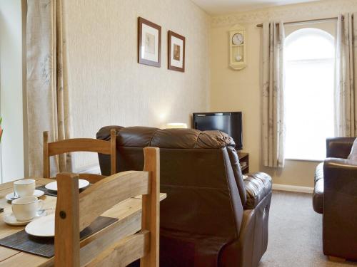 a living room with a leather couch and a table at Eldin Hall Cottage 1 - Uk2483 in Cayton