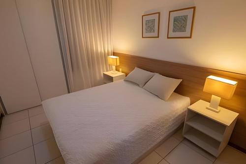 a small bedroom with a white bed with two lamps at Iloa Residence 103A in Barra de São Miguel