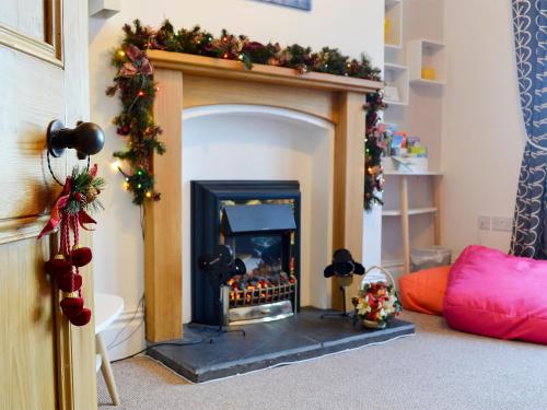 a living room with a fireplace with christmas decorations at Zonnebloem in Cefn-y-bedd