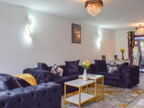 a living room with blue couches and a table at West Park House in Penwortham