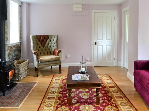a living room with a purple couch and a coffee table at Roseburn Cottage in Moffat