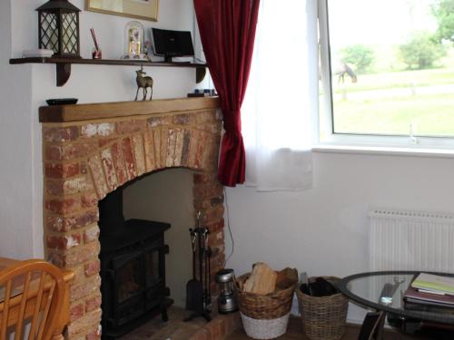 a fireplace in a living room with a table and a window at Brookside in Ellingham