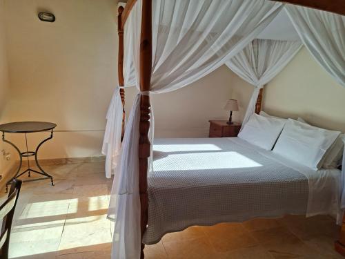 a bedroom with a canopy bed and a table at Kleanthis House in Tochni